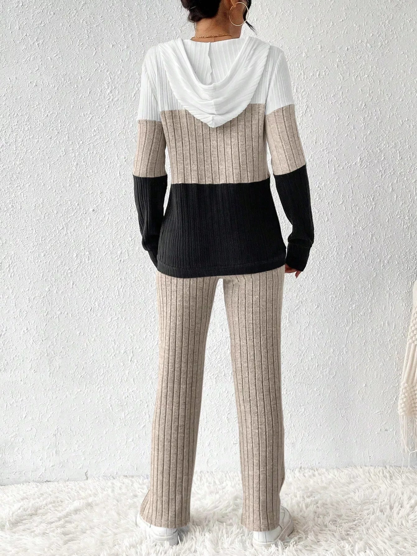 Woman wearing a dust storm, black and white color block half zip hooded top with matching ribbed-look pants.