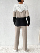 Woman wearing a dust storm, black and white color block half zip hooded top with matching ribbed-look pants.