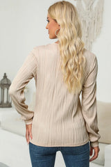 Woman wearing a dust storm textured round neck long sleeve blouse with dark-wash jeans.