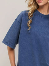 Woman wearing an oversized dusty blue Basic Bae round-neck half-sleeve T-shirt styled with dark denim jeans and a long pendant necklace for a relaxed, casual look.