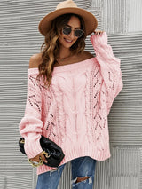 Woman wearing a dusty pink cable knit openwork off-shoulder sweater with distressed jeans and a wide-brim hat.