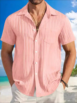 Man wearing a dusty pink textured short sleeve button-up shirt with white pants for a polished casual summer look.
