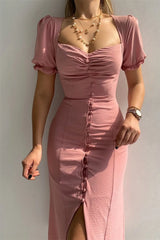 Woman wearing a dusty pink sweetheart-neck midi dress with puff sleeves, ruched detailing, and a button-front slit.