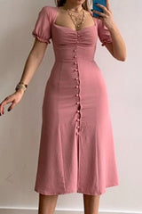 Woman wearing a dusty pink sweetheart-neck midi dress with puff sleeves, ruched detailing, and a button-front slit.
