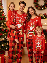 Family wearing matching red Santa Christmas pajama tops with red and black plaid holiday pants beside a decorated Christmas tree.