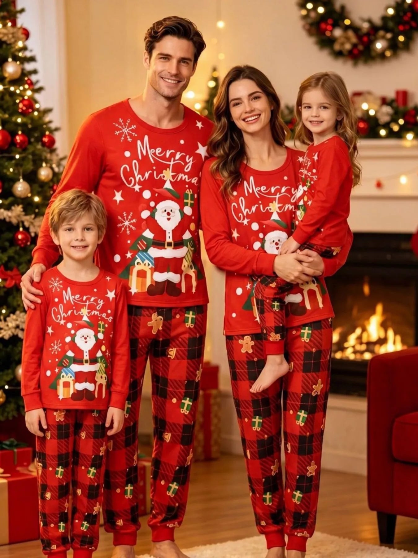Family wearing matching red Santa Christmas pajama tops with red and black plaid holiday pants beside a decorated Christmas tree.