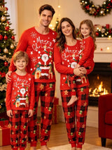 Family wearing matching red Santa Christmas pajama tops with red and black plaid holiday pants beside a decorated Christmas tree.
