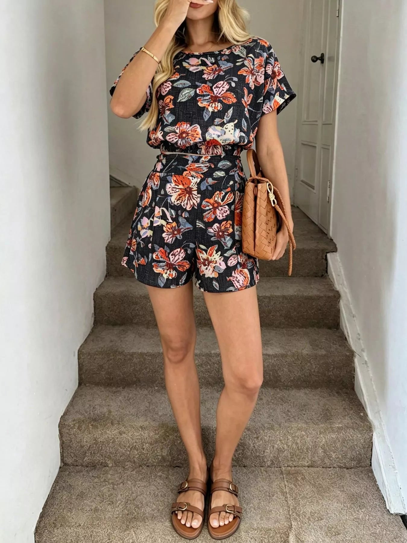 Woman in a floral romper standing on a staircase