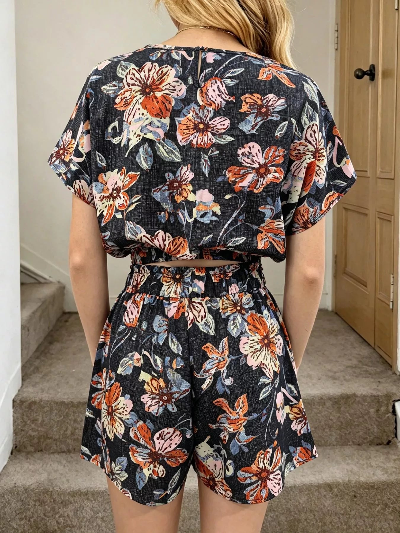 Person wearing a floral romper with a neutral background
