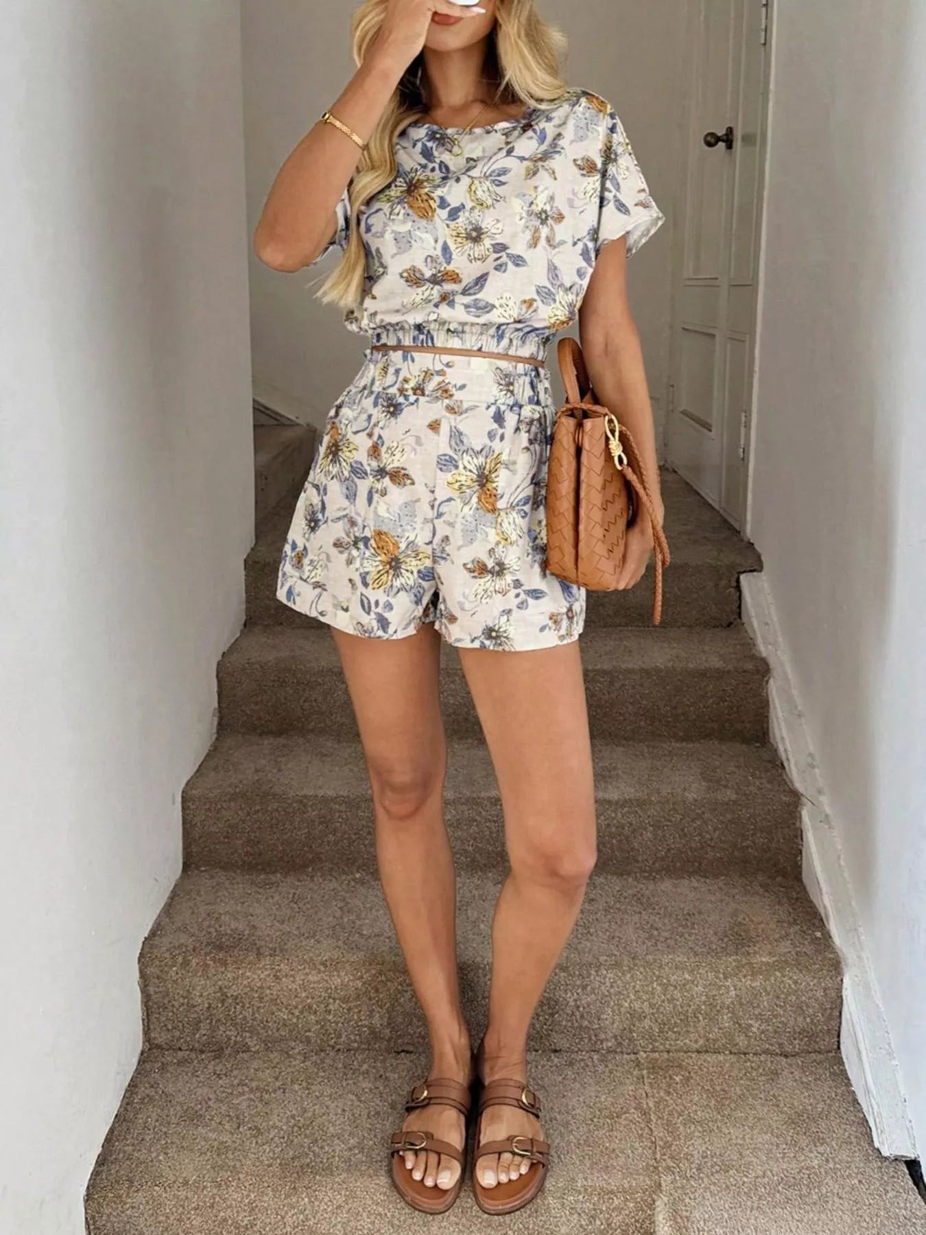 Woman in a floral outfit in Off White standing on a staircase