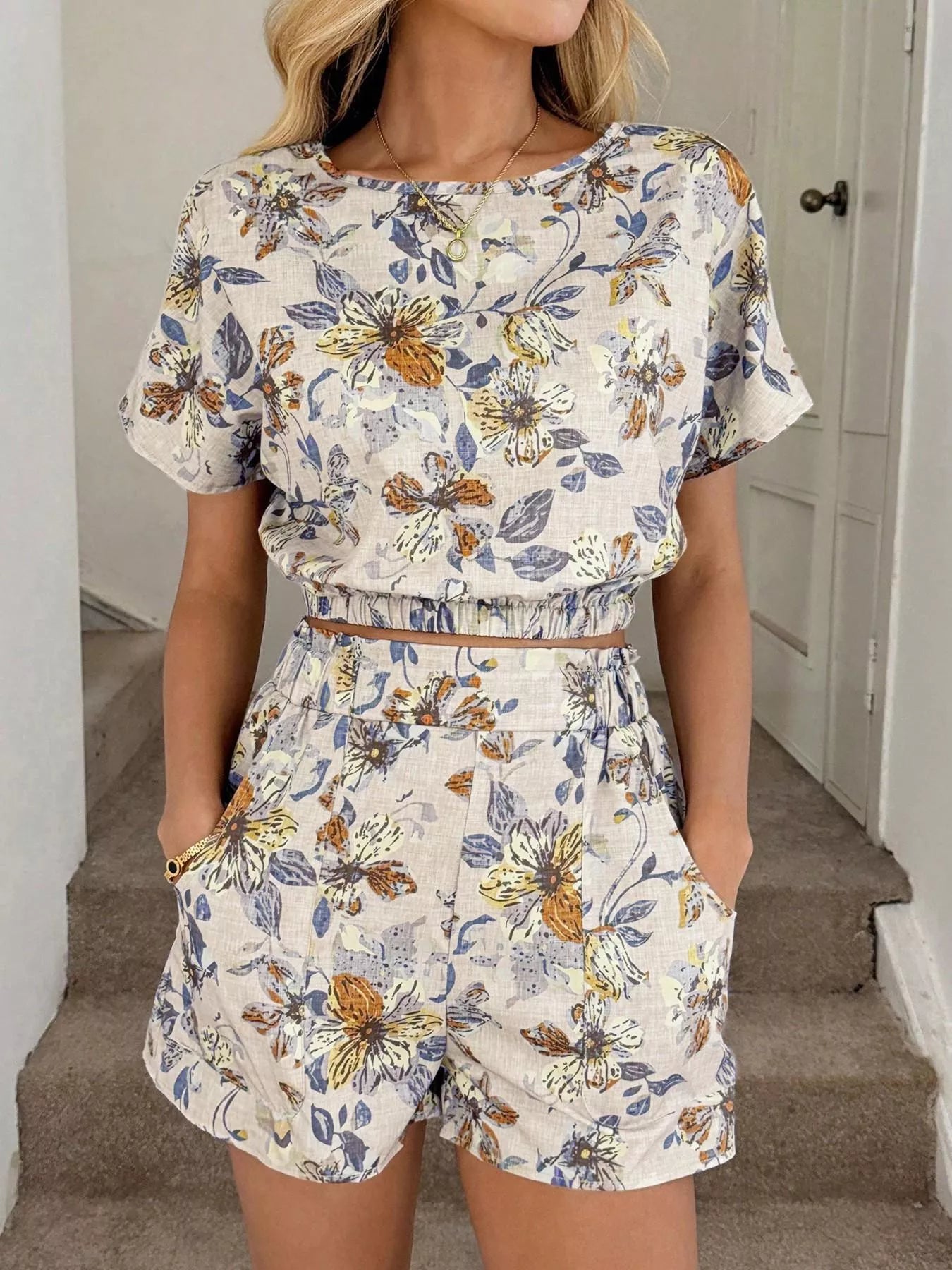 Person wearing a floral romper in Off White standing on a staircase.