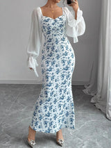Woman wearing a floral dress with sheer sleeves in an indoor setting