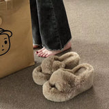 Pair of fluffy slippers on a carpeted floor with a cardboard bag in the background.