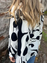 Person wearing a black and white patterned shirt with a blurred background showcasing the back of the shirt.