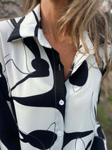 Close-up of a person wearing a black and white patterned shirt with abstract designs.