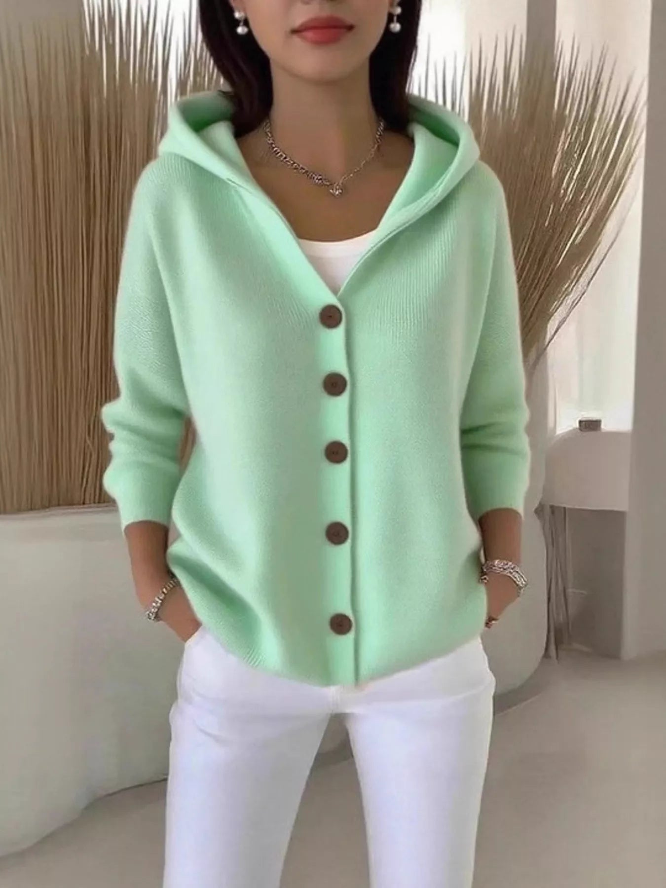 Women's green button-up knit cardigan with hood and front pockets, long sleeve lightweight sweater styled with white pants, available in sizes Small–5XL.