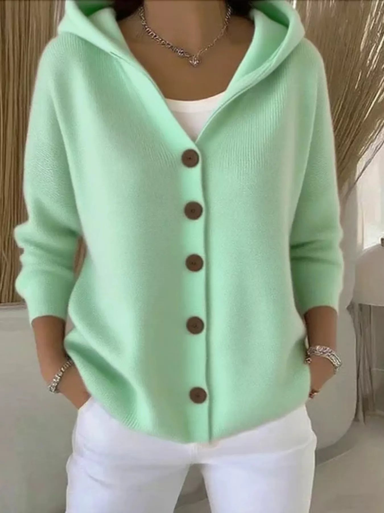 Women's green button-up knit cardigan with hood and front pockets, long sleeve lightweight sweater styled with white pants, available in sizes Small–5XL.