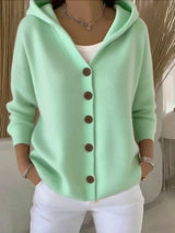Women's green button-up knit cardigan with hood and front pockets, long sleeve lightweight sweater styled with white pants, available in sizes Small–5XL.