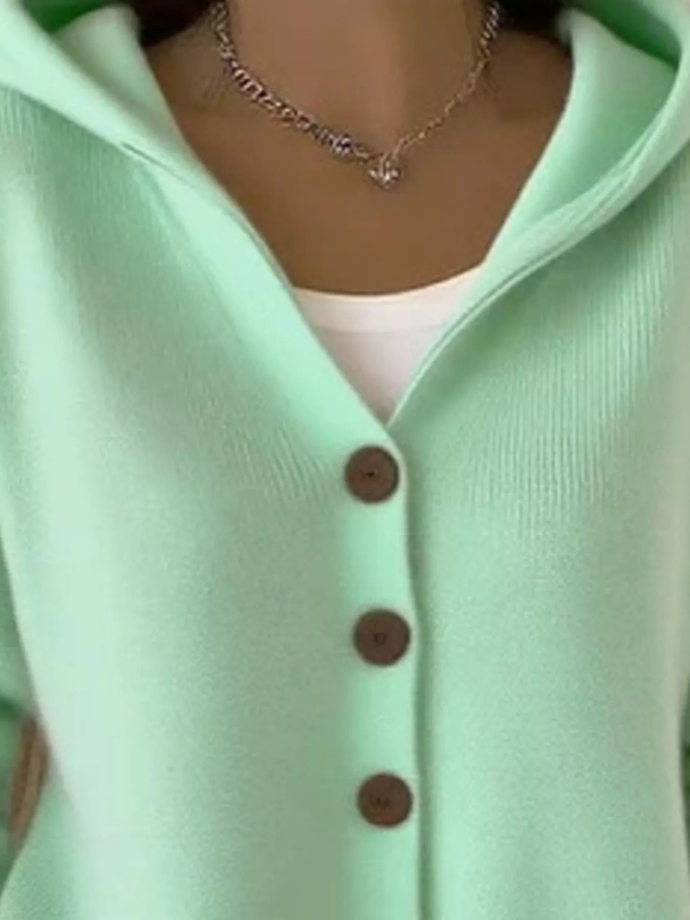Women's green button-up knit cardigan with hood and front pockets, long sleeve lightweight sweater styled with white pants, available in sizes Small–5XL.