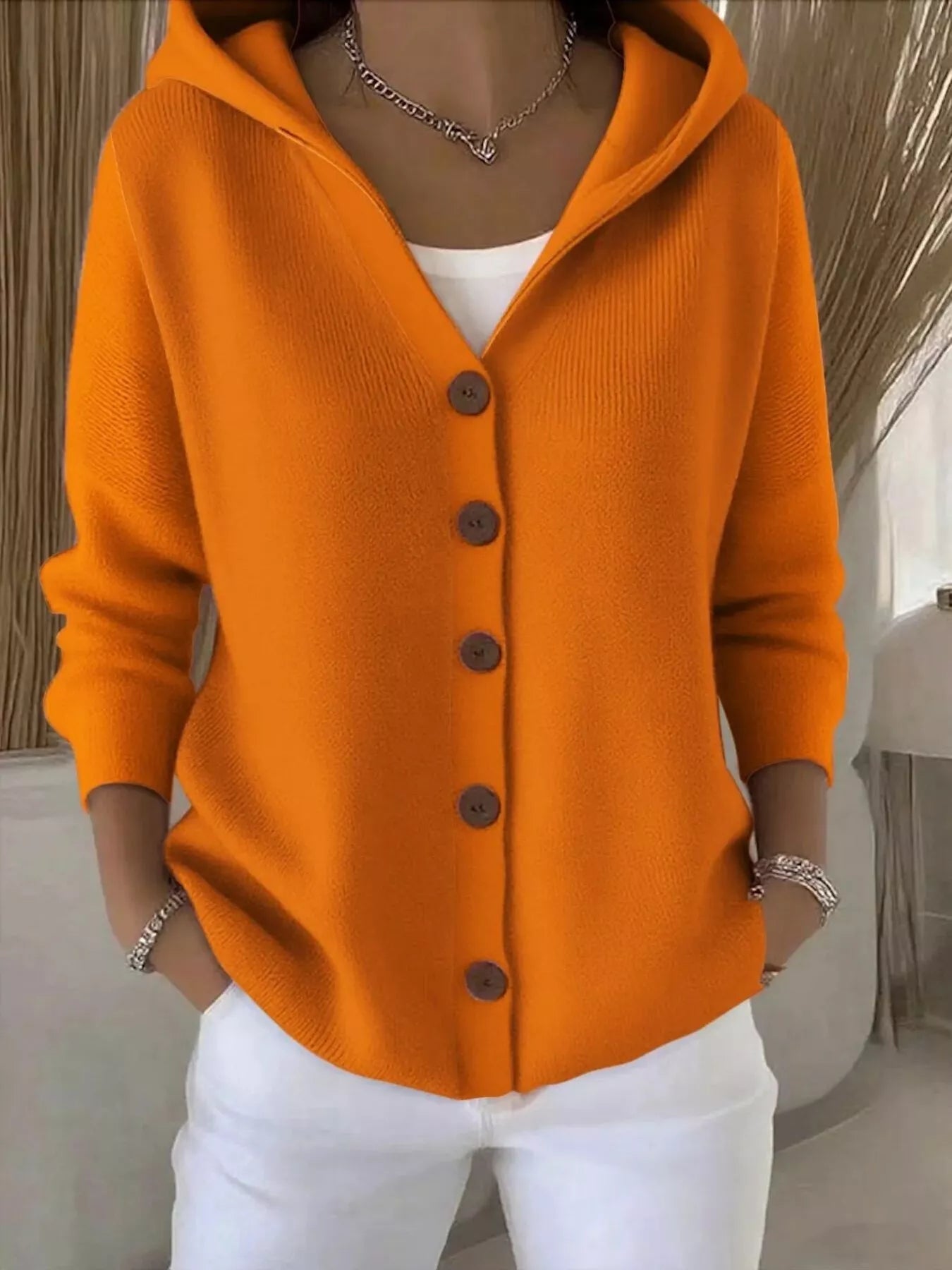 Women's orange button-up knit cardigan with hood and front pockets, long sleeve lightweight sweater styled with white pants, available in sizes Small–5XL.