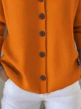 Women's orange button-up knit cardigan with hood and front pockets, long sleeve lightweight sweater styled with white pants, available in sizes Small–5XL.