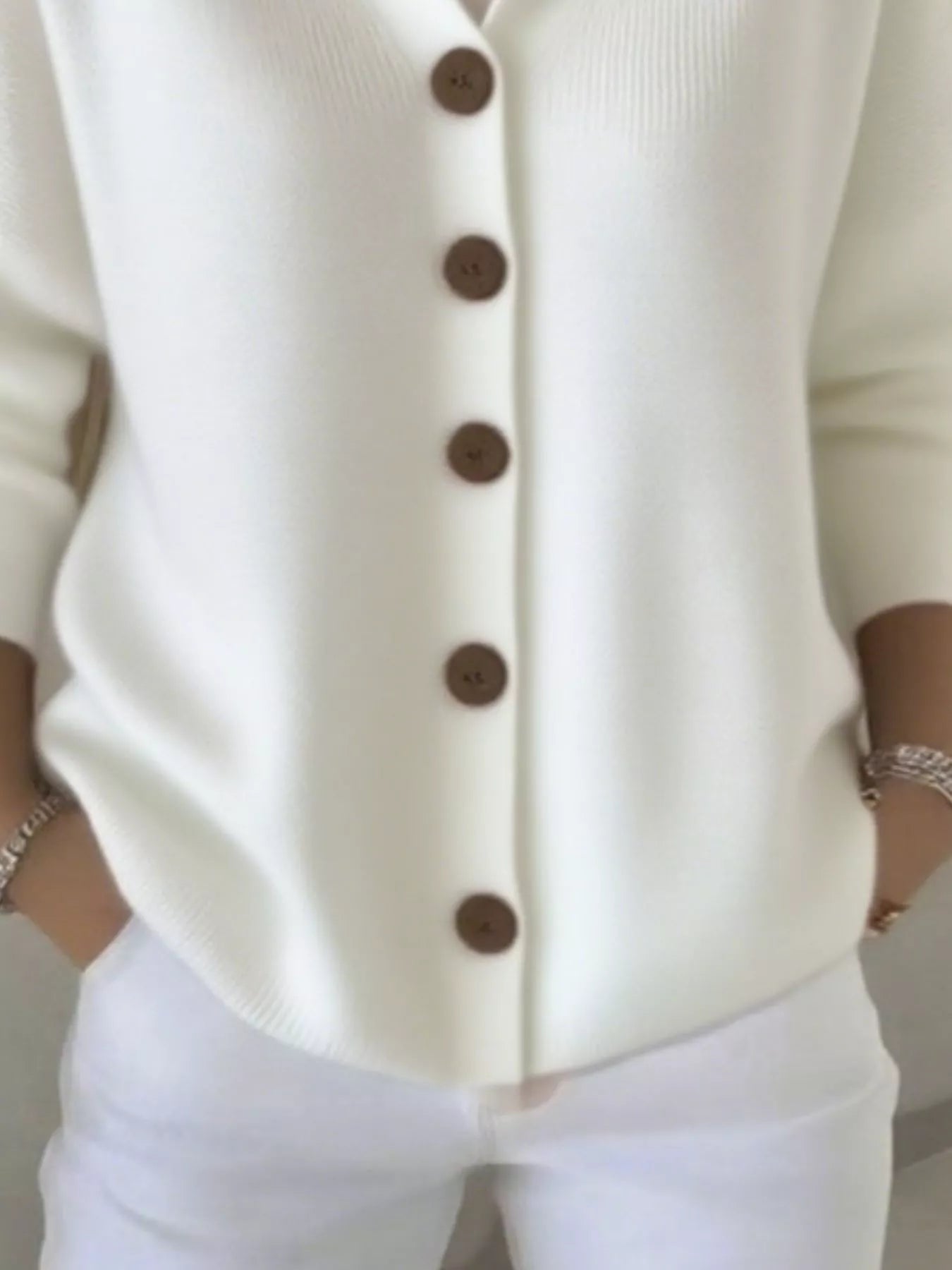 Women's white button-up knit cardigan with hood and front pockets, long sleeve lightweight sweater styled with white pants, available in sizes Small–5XL.