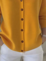 Women's yellow button-up knit cardigan with hood and front pockets, long sleeve lightweight sweater styled with white pants, available in sizes Small–5XL.
