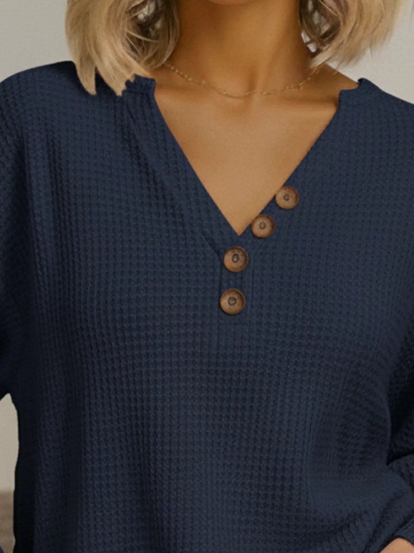Navy blue textured shirt with brown buttons worn by a person.