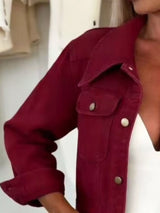 Woman wearing a wine red cropped denim jacket over a white top with light-wash jeans and a structured handbag, styled for a chic fall outfit.
