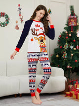 Mom wearing matching Christmas reindeer pajamas with navy sleeves, red trim, smiling Santa-hat reindeer graphics and festive patterned pants.