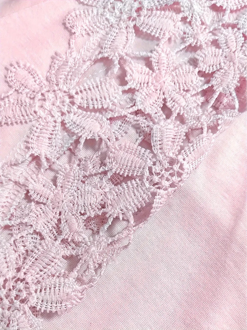 Close-up of white lace on a pink fabric background