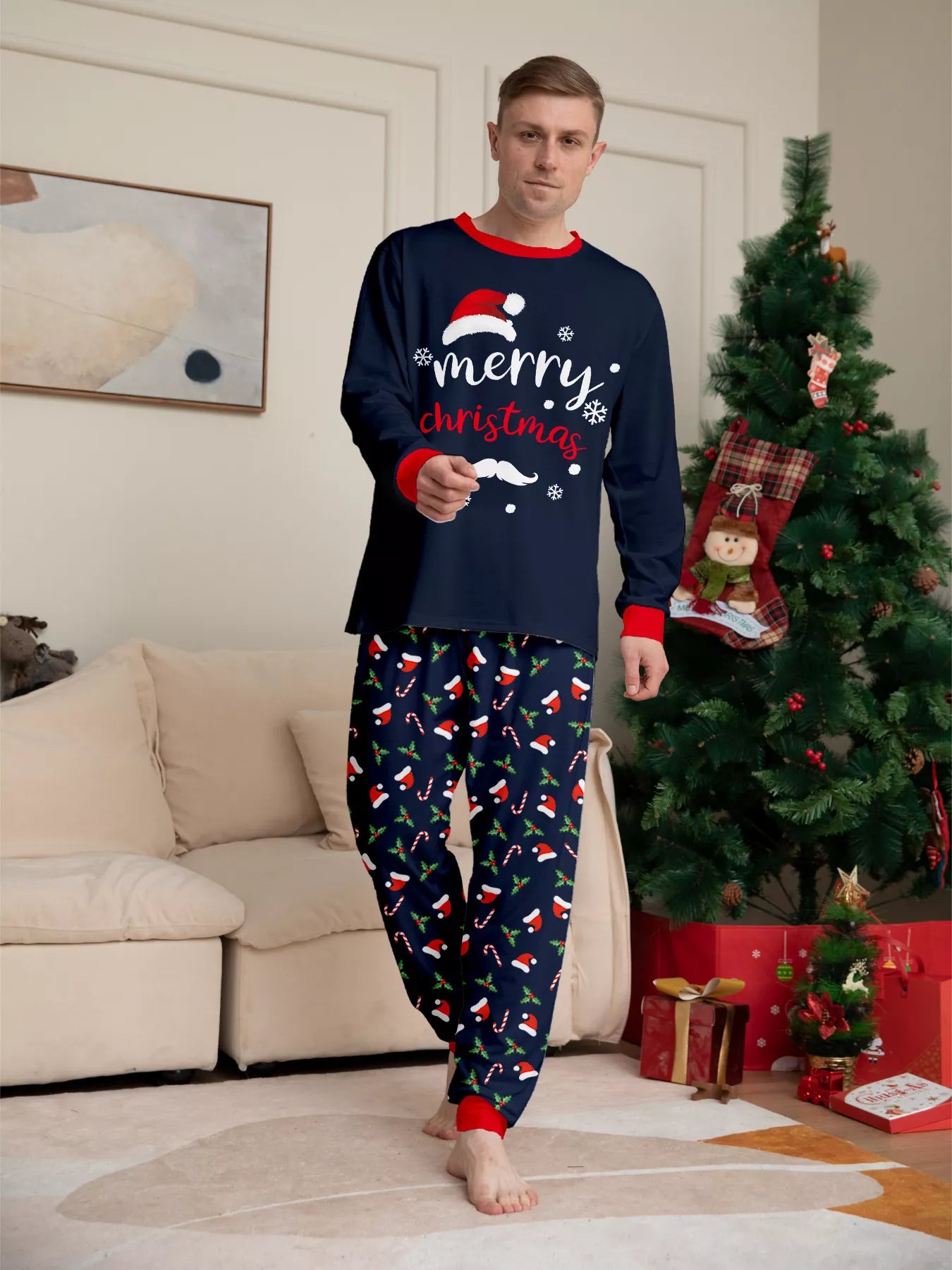 Man wearing navy blue Merry Christmas pajama sets with red trim and holiday-print pants.