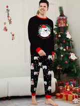 Dad wearing matching black Christmas pajamas with polar bear print, colorful holiday lights and red trim beside a Christmas tree.