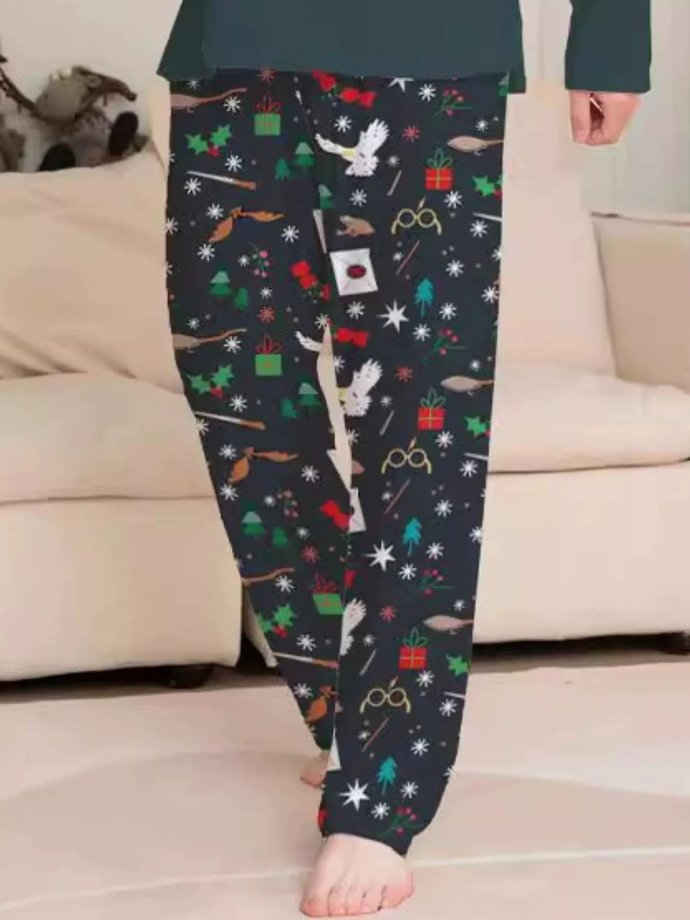 Family wearing matching dark green Hogwarts graphic Christmas pajama tops with coordinating navy holiday print pajama pants.