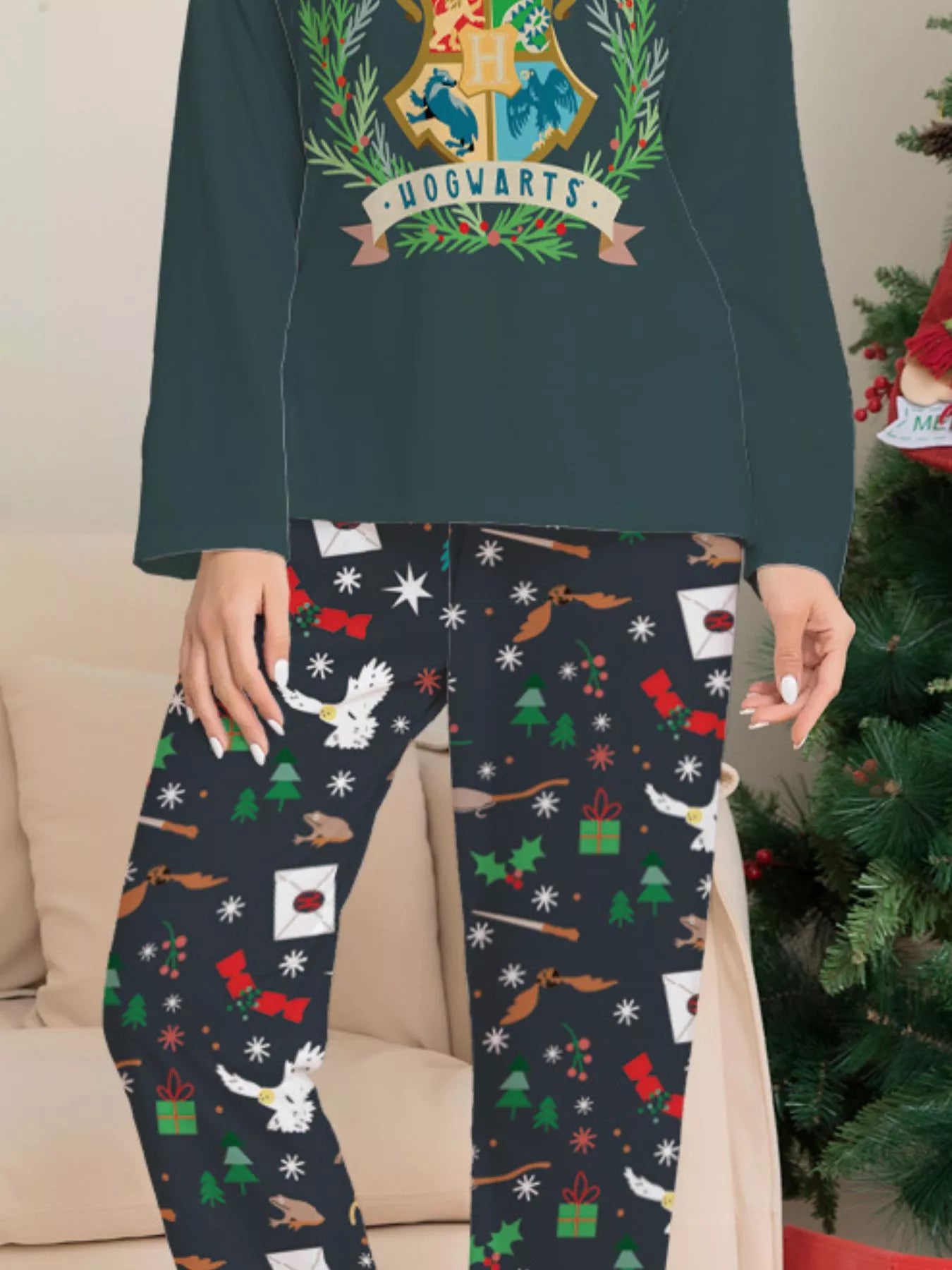 Family wearing matching dark green Hogwarts graphic Christmas pajama tops with coordinating navy holiday print pajama pants.