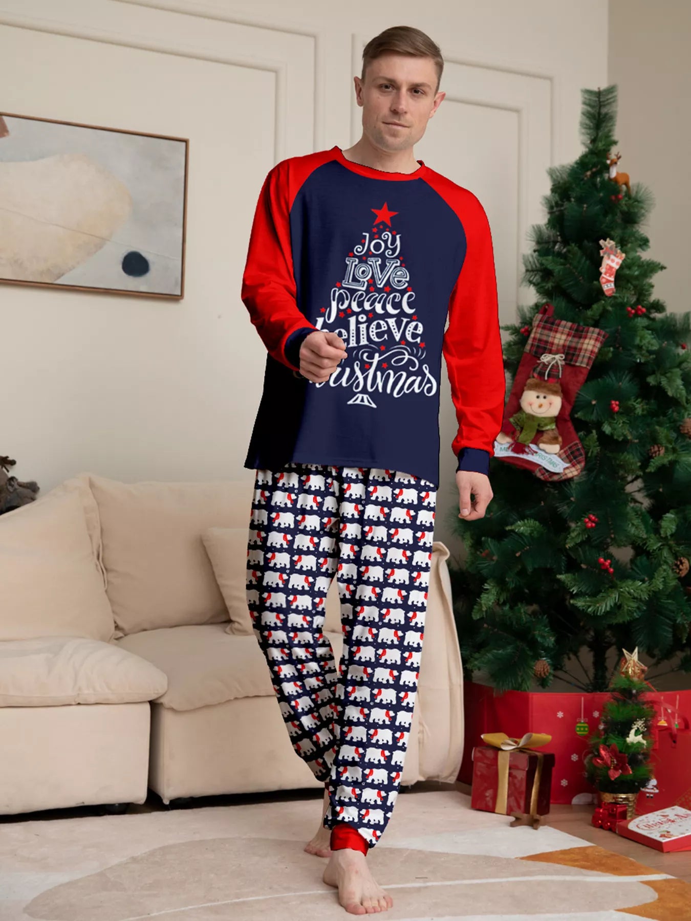 Dad wearing matching Christmas pajamas with navy tops, red raglan sleeves, festive Christmas tree lettering, and coordinating printed pants.