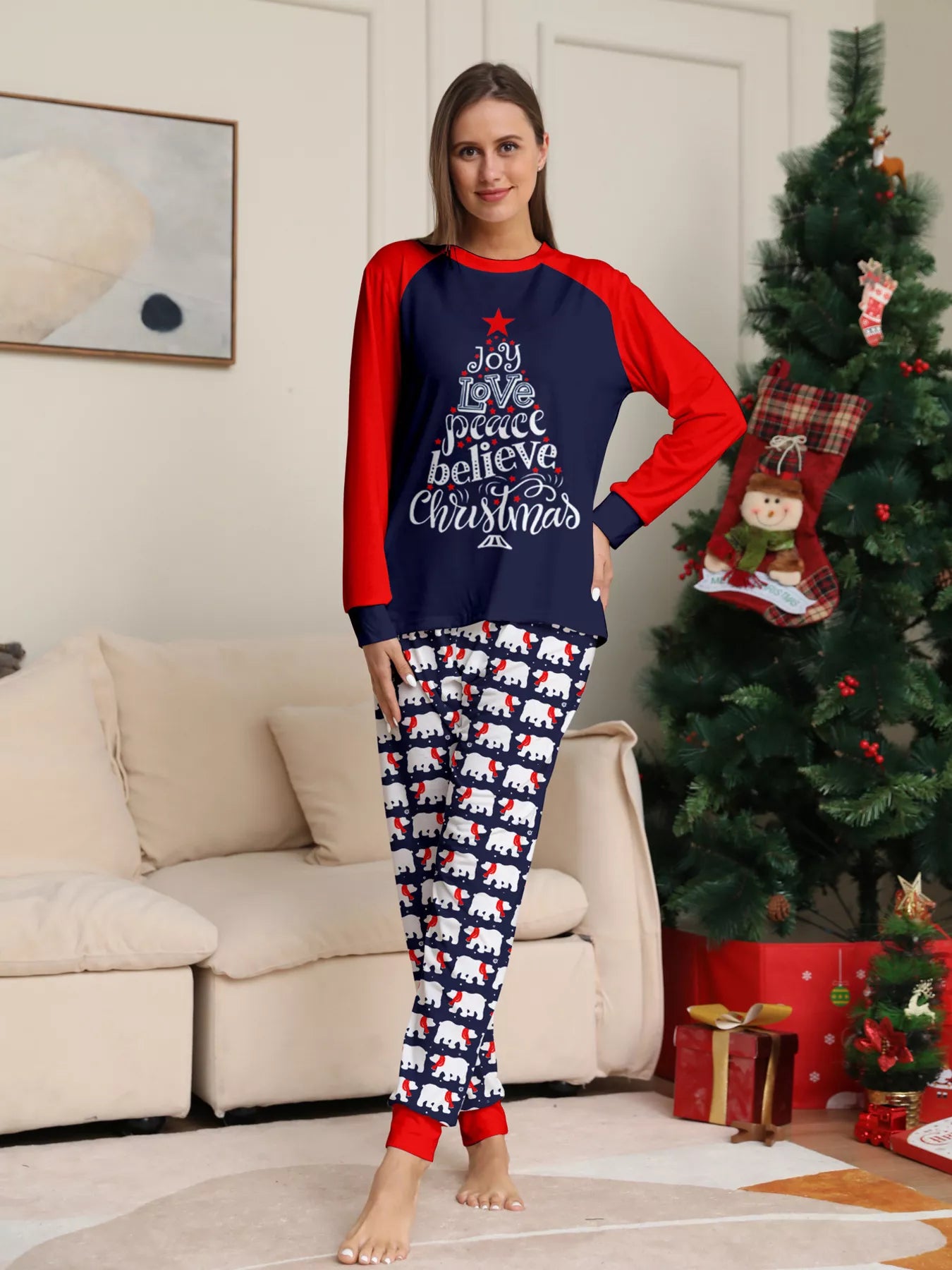 Mom wearing matching Christmas pajamas with navy tops, red raglan sleeves, festive Christmas tree lettering, and coordinating printed pants.