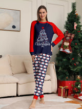 Mom wearing matching Christmas pajamas with navy tops, red raglan sleeves, festive Christmas tree lettering, and coordinating printed pants.