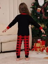 Girl wearing matching Christmas Crew graphic pajama set back with black long-sleeve tops and red buffalo plaid pants.