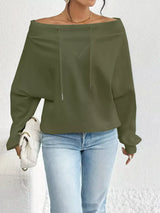 Person wearing an olive green off-shoulder top and light blue jeans against a white background