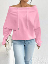 Person wearing a pink off-shoulder top and light blue jeans against a white background