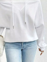 White blouse with long sleeves and light blue jeans on a neutral background
