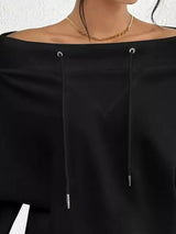 Black off-shoulder top with lace-up details on a white background