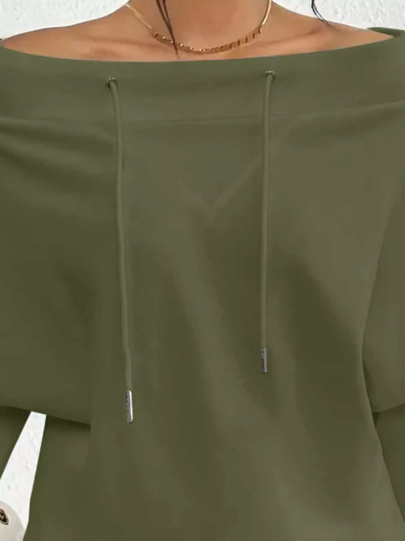 Green off-shoulder top with drawstrings on a neutral background