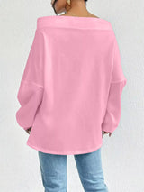 Person wearing a pink oversized sweater against a white background showing the back of top.