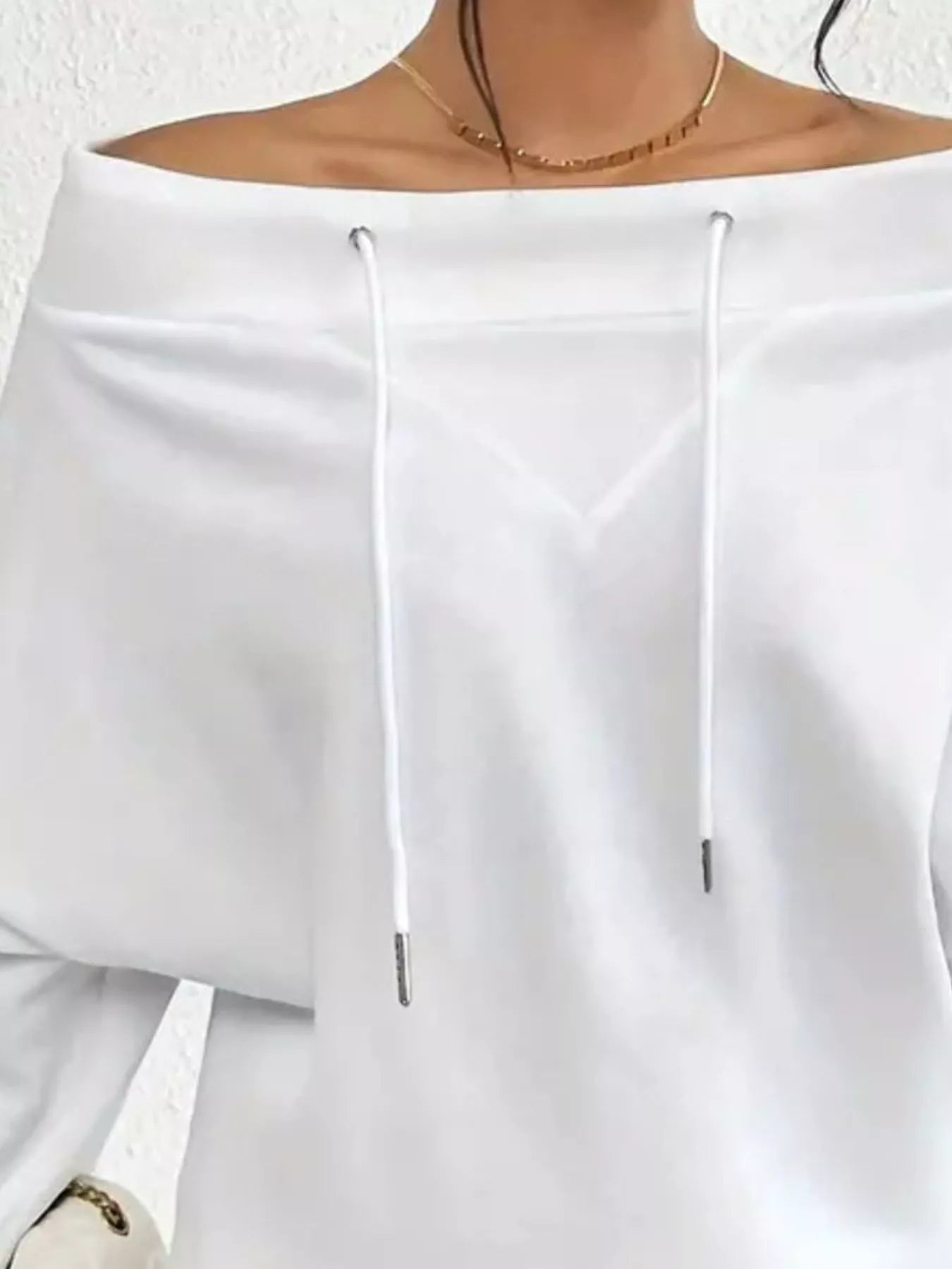 White off-shoulder top worn by a person on a white background