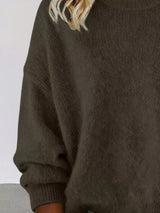Woman wearing a dark brown round neck dropped shoulder sweater with dark-wash jeans.