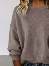Woman wearing a dark gray round neck dropped shoulder sweater with dark-wash jeans.