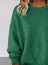 Woman wearing a green round neck dropped shoulder sweater with dark-wash jeans.