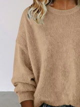 Woman wearing a Khaki round neck dropped shoulder sweater with dark-wash jeans.